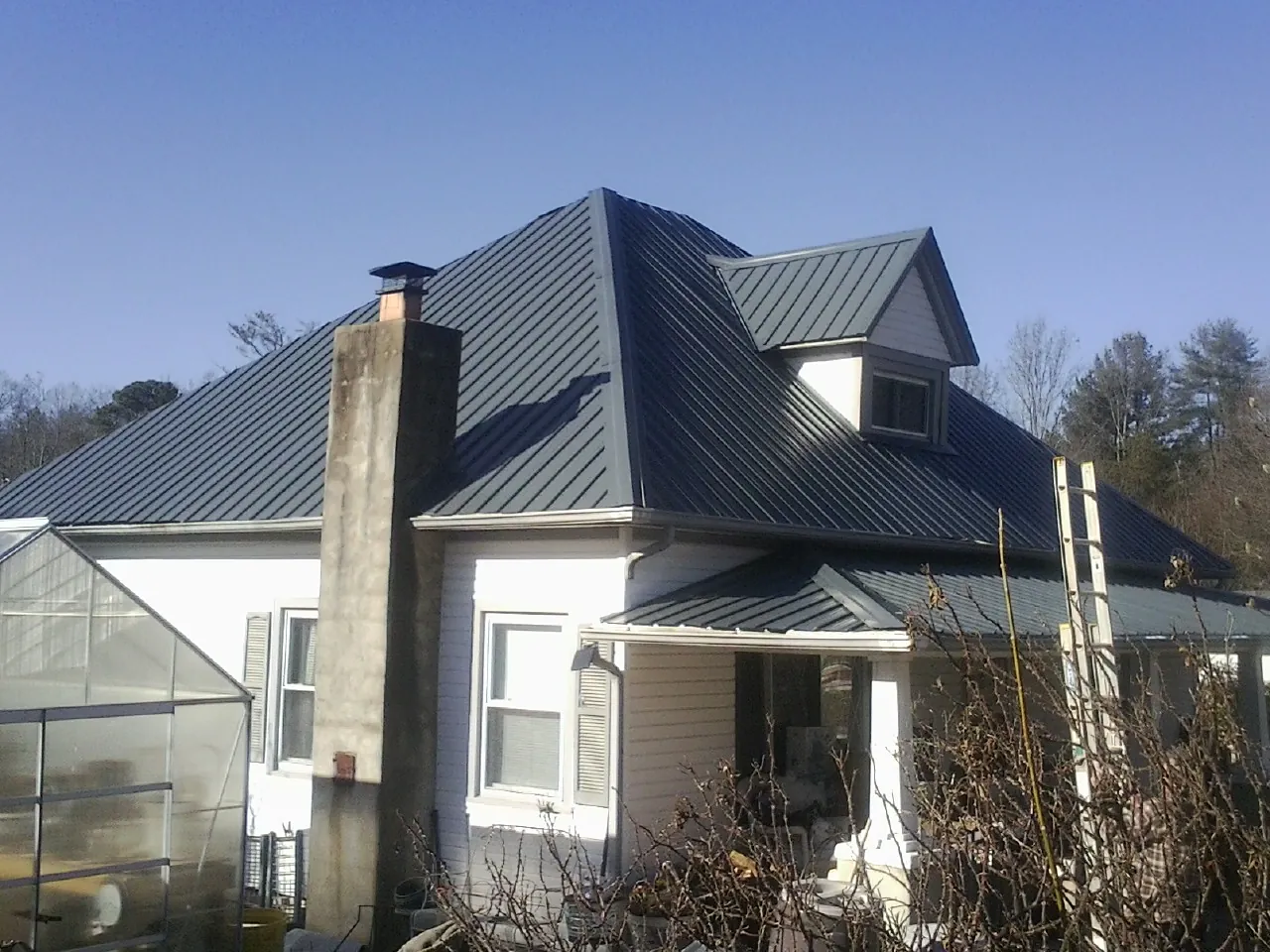 Dark blue standing seam metal roof on a white farmhouse with dormer — Slate & Tile Roof Repair by Roofing Brothers in Rockport