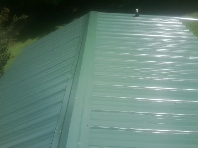 New green metal panels meeting at the ridge of a roof — Flat Roof Repair work by our crew in Rockport