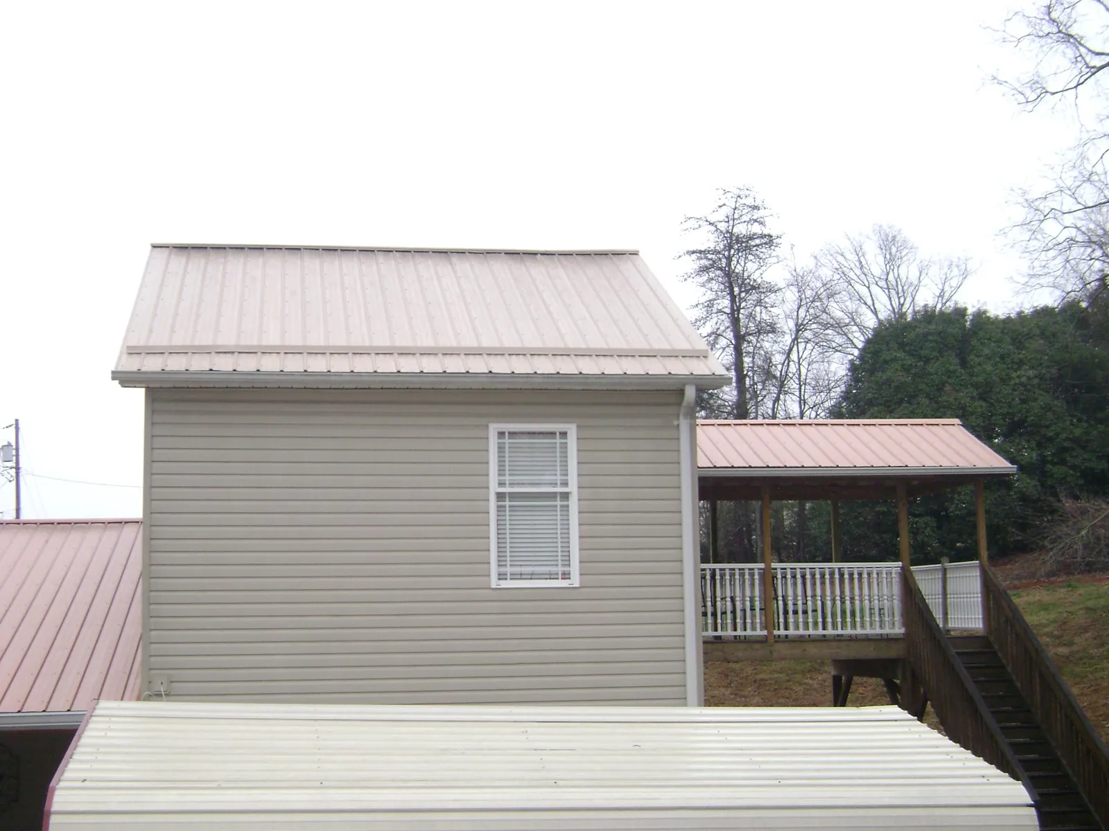 Tan metal roofs on a two story addition and attached porch, from a Roof Replacement job in Rockport