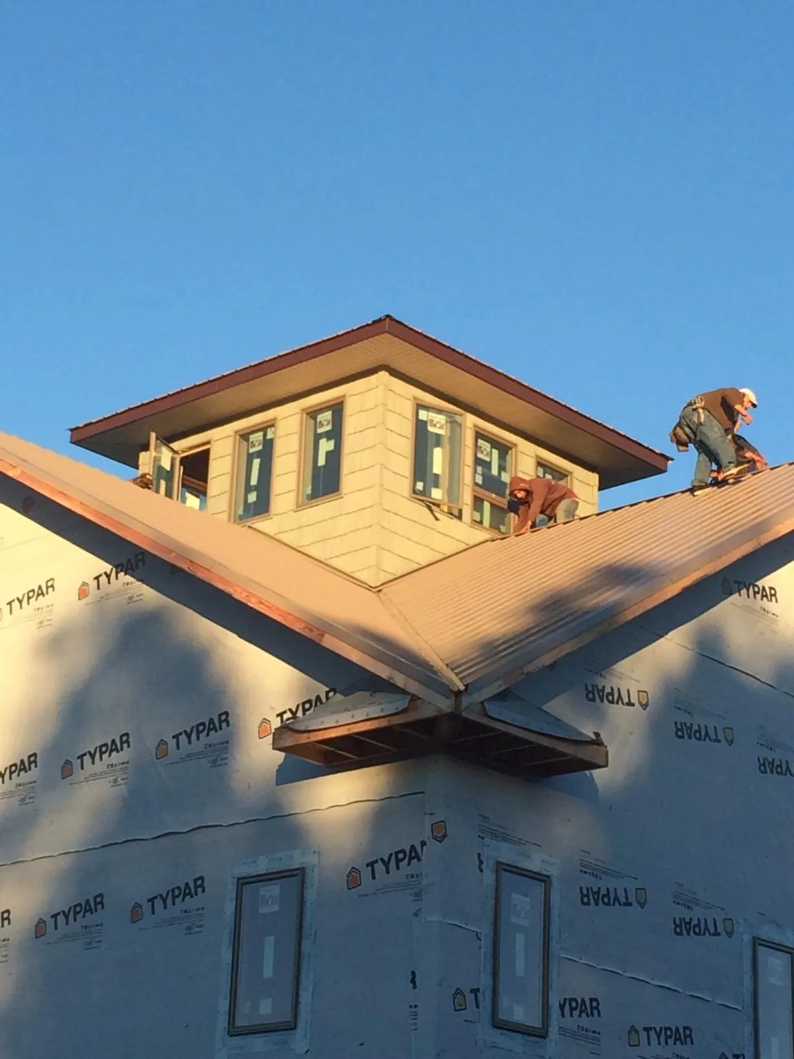 Roofers working around a rooftop cupola on a new metal roof at sunset — Roof Waterproofing in Rockport by Roofing Brothers